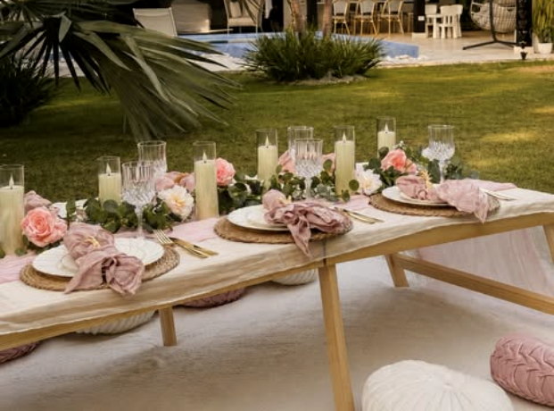Private garden picnic table set with blush linens, roses and candles.